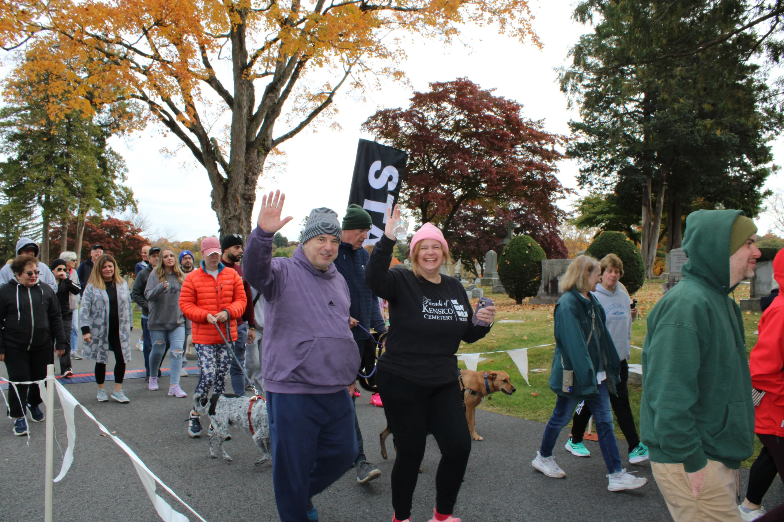 Pathway with mausoleums surrounded by trees with leaves changing color for autumn