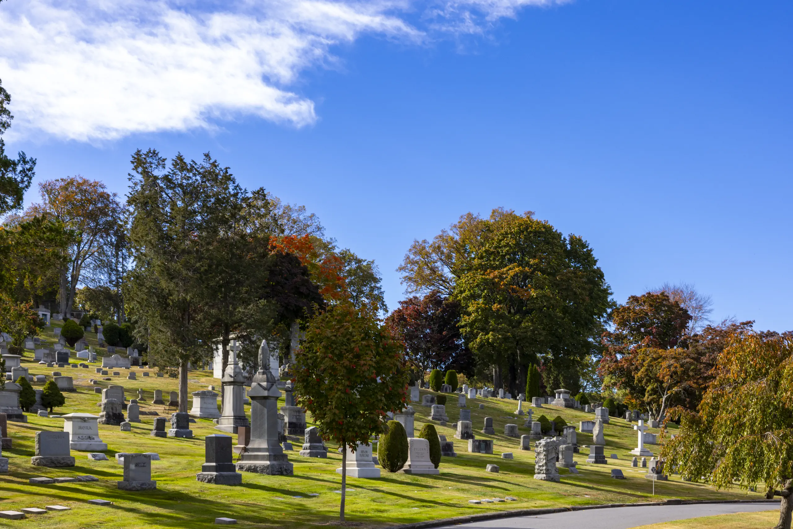Pathway with mausoleums surrounded by trees with leaves changing color for autumn